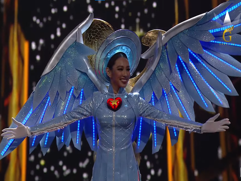 Ở phần kết đêm thi quốc phục, một bên cánh "thiên thần" trang phục của Thùy Tiên không may bị cụp xuống. Gặp sự cố nhỏ, Thùy Tiên xử lý tình huống nhanh và bước vào trong. Sau đêm thi, Thùy Tiên hé lộ hình ảnh hai cánh tay bị thương. Người đẹp chia sẻ trên Ngôi sao, do phần tay áo bị chật nên khi vận động trong hậu trường, cô bị tụ máu. Khi lên trình diễn, Thùy Tiên quyết định bỏ bớt đôi găng tay boxing để dễ dàng vận động. Ảnh: Sen Vàng