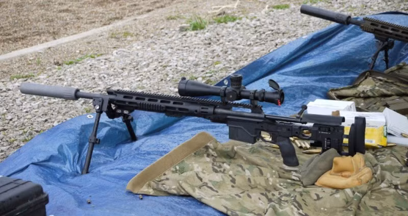 Báng súng được thiết kế dạng khung, mỏng và gọn nhẹ với chất liệu chính bằng nhôm và được lót đệm polymer ở các vị trí tiếp xúc với vai cũng như má của xạ thủ. Báng cũng có khả năng có thể điều chỉnh được độ cao và độ dài nhờ hai bánh xe ngang và dọc để phù hợp với thể trạng của xạ thủ.