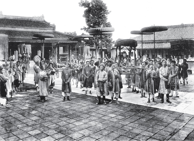 Vua Duy Tân ngự giá tại hoàng thành ở Huế. Các thị vệ đứng xung quanh để bảo vệ nhà vua và đảm bảo an ninh.