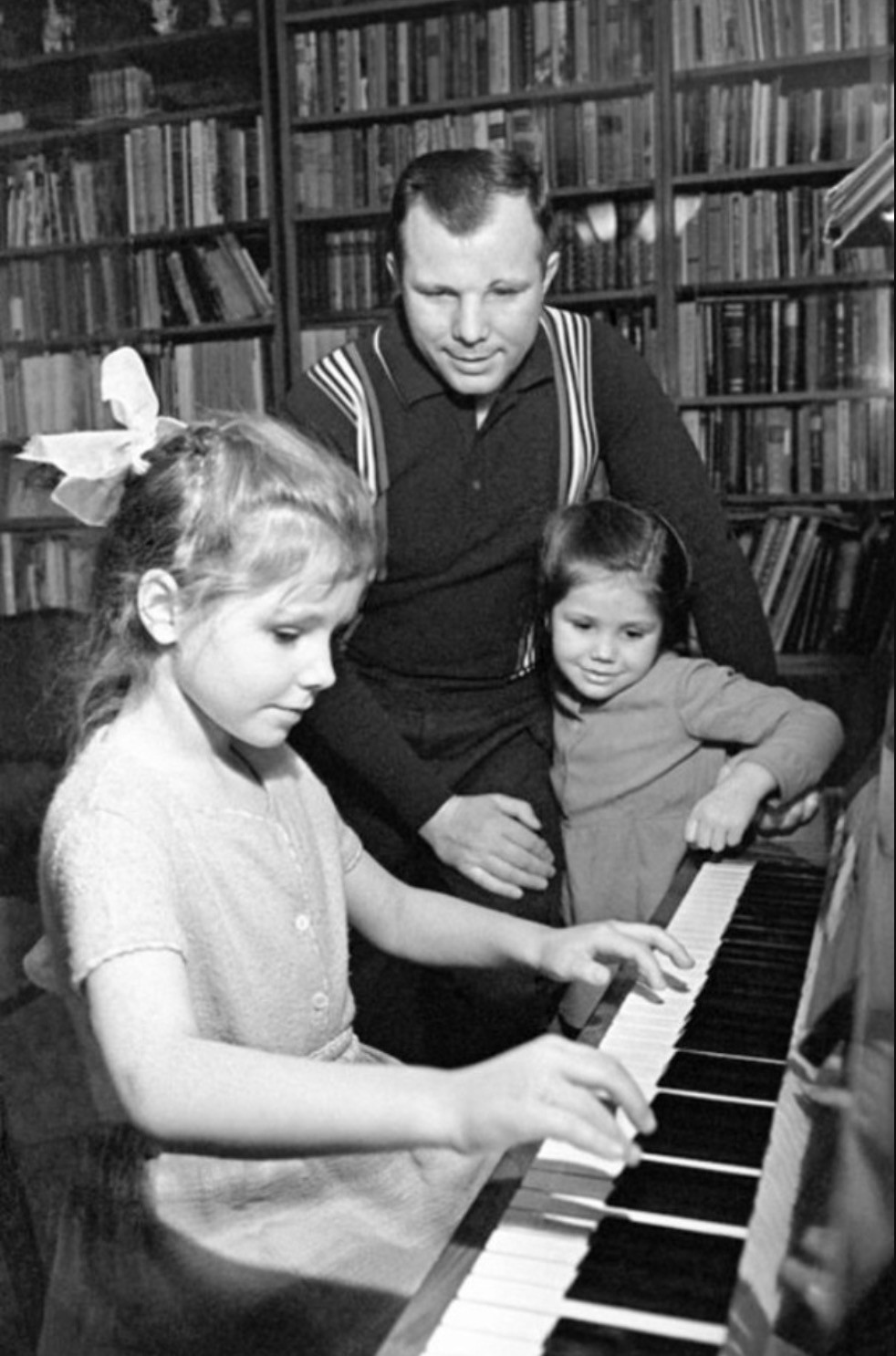 Nhà du hành vũ trụ Gagarin có 2 con gái. Con gái lớn của ông đánh đàn piano trong khi Gagarin và con gái út đứng bên cạnh chăm chú lắng nghe, cổ vũ.