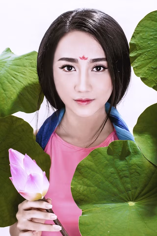 Lona Huỳnh còn đưa hình ảnh hoa sen vào trong bộ ảnh của mình như một dấu ấn về văn hóa truyền thống. Bông sen hồng cùng màu sắc với tấm yếm đào khiến cô hot girl trông rất quyến rũ.