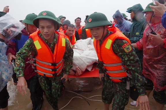 Các thuyền viên sau khi được các chiến sĩ đặc công nước dìu về bờ an toàn đã nhanh chóng được đưa đi chăm sóc y tế đặc biệt sau một thời gian dài bị cô lập, sóng đánh liên hồi và luôn trong trạng thái lo âu bởi khả năng có thể bị nước cuốn đi. Ảnh: Bộ đội biên phòng đưa người bị nạn vào bờ - Nguồn: QĐND Online.