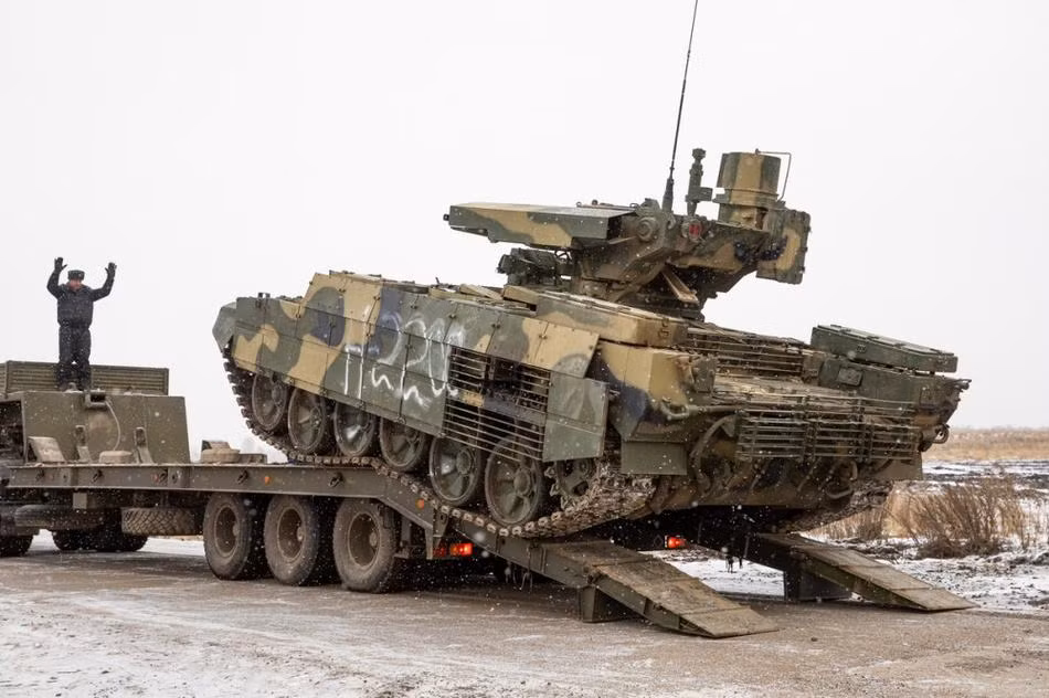 Về động cơ, xe có thể sử dụng động cơ diesel đa nhiên liệu V-84MS công suất 840 mã lực hoặc V-92S2 công suất 1.000 mã lực. Hộp số của xe là hộp số sàn truyền thống trên T-72 với 7 số tiến và 1 số lùi. Ngoài ra xe cũng được lắp đặt một động cơ điện phụ trợ APU có thể tạo ra công suất từ 5 - 8kW tùy cấu hình, được đặt ở phía sau bên phải của xe. Điều này giúp xe có thể vận hành các hệ thống điện và vũ khí trong xe mà không cần khởi động máy chính, giúp tiết kiệm đáng kể nhiên liệu và độ ẩn mình. Ảnh: BMPT-72 di chuyển xuống khỏi xe vận tải.