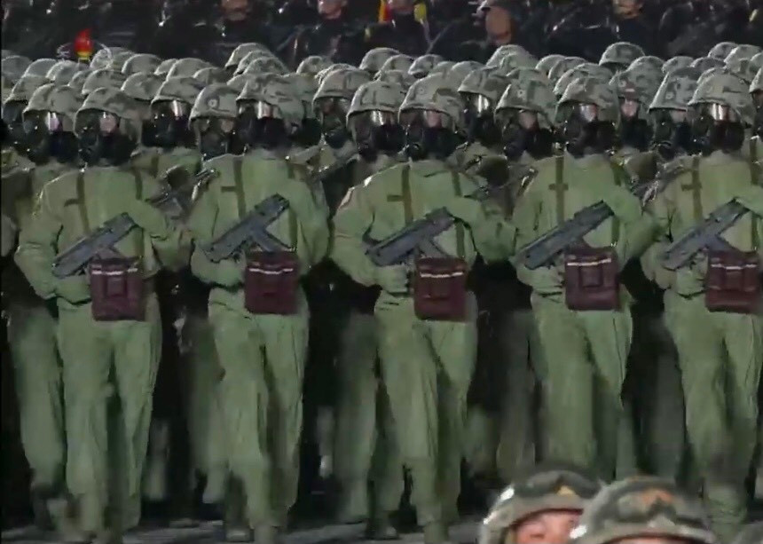 Khối chiến sĩ hóa học với bộ quần áo chống chất độc phóng xạ, mặt nạ phòng hóa, mũ chống đạn, túi đựng dụng cụ máy móc kiểm tra môi trường và súng trường Type-88 súng gập. Khác với mọi năm, lực lượng hóa học Triều Tiên nay đã lột xác với một màn xuất hiện cực kỳ thu hút.