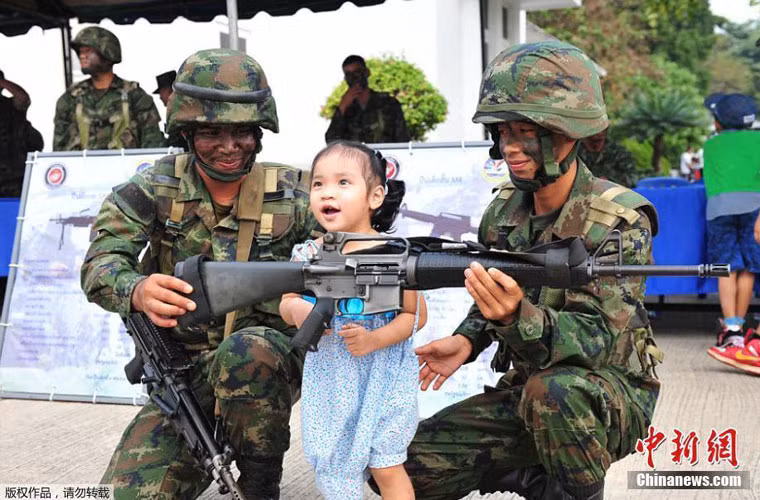 Một bé gái tỏ ra rất thích thú khi lần đầu tiên được chạm vào khẩu súng, nên đã không ngại khi chụp ảnh kỷ niệm cùng với hai binh lính của quân đội Thái Lan.
