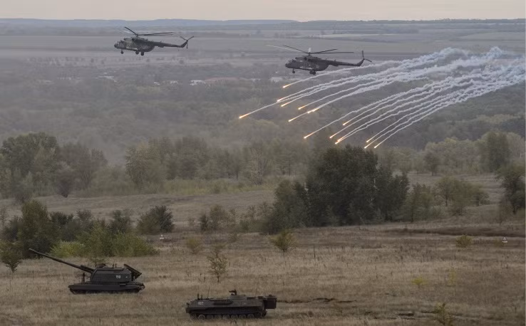 Hệ thống pháo tự hành MSTA-S hành quân với sự hộ tống của các trực thăng Mi-8 vừa bay vừa bắn pháo sáng thị uy sức mạnh.