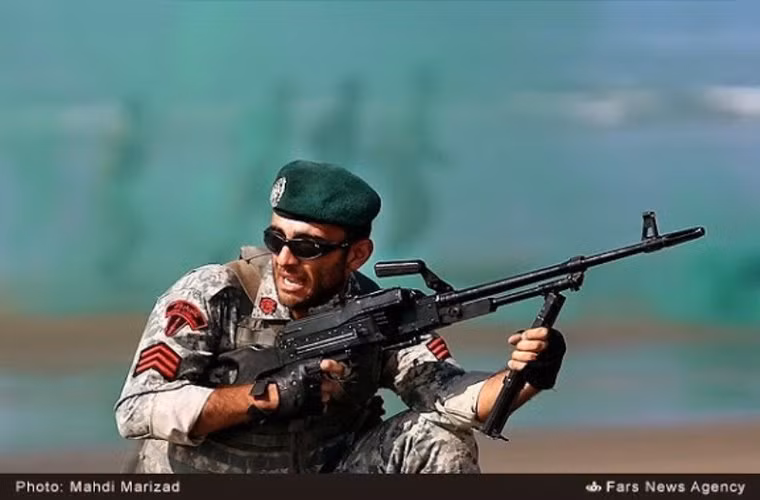 Hạ sĩ quan nhất của Thủy quân lục chiến Iran đang tiến công lên đất liền từ tàu đệm khí với khẩu súng máy PKM có tốc độ bắn 650 phát/phút và tầm bắn hiệu quả tới 1000 m.