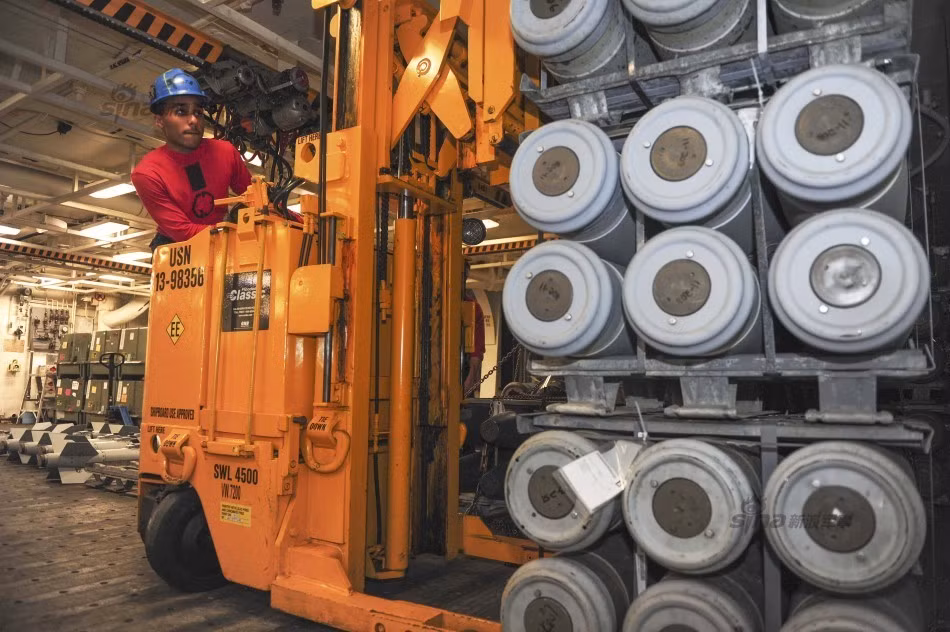 Một loạt bom được xếp chồng cẩn thận lên nhau và được xe chở chuyên dụng đưa ra khỏi kho chứa vũ khí trên tàu sân bay.