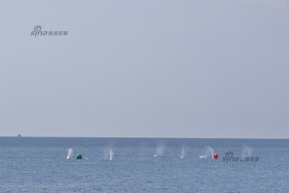 Những viên đạn xoay xung quanh vùng mục tiêu giả định được đánh dấu bằng hai quả bóng xanh và đỏ nổi trên mặt biển.