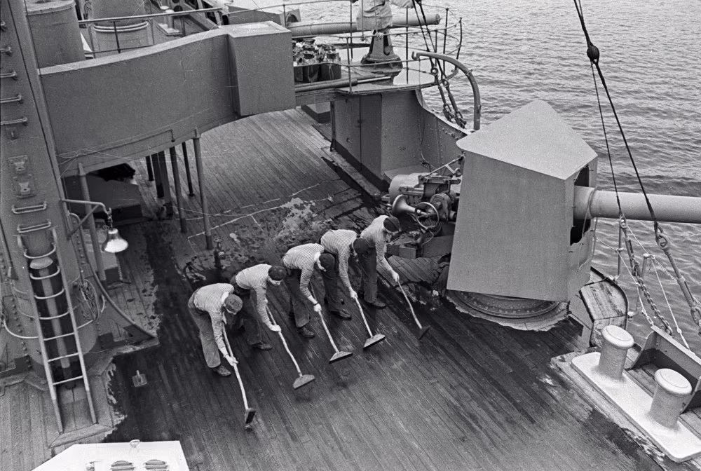 Tuần dương hạm Rạng Đông dài 126,8 mét, trọng tải dãn nước 6.731 tấn. Vũ khí ban đầu của con tàu gồm pháo và ngư lôi. Ảnh: các thủy thủ đang lau dọn sàn tàu.