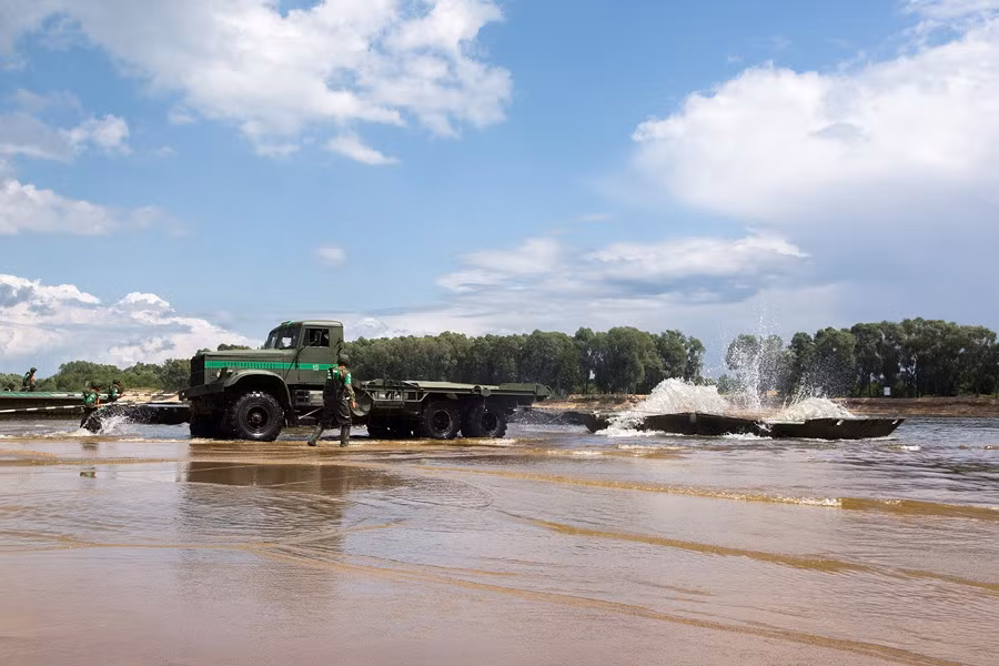 Một xe tải đang thả các đốt cầu phao xuống sông.