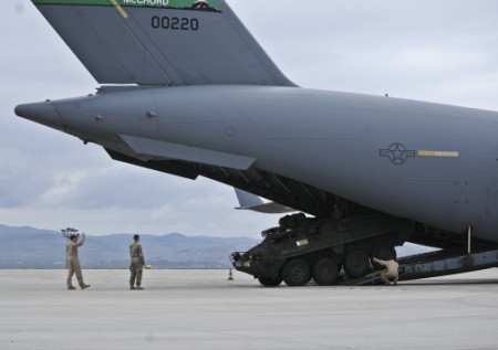 Máy bay đang "nhả" từng chiếc xe Stryker ra sân bay.