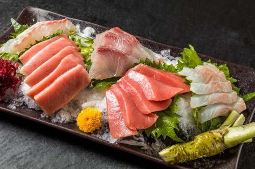 2. Sashimi. Sashimi là món ăn truyền thống Nhật Bản với thành phần là các loại hải sản tươi sống. Sashimi không qua xử lý nhiệt, thường ăn cùng các loại nước chấm như xì dầu, tương, wasabi, gừng và một số loại rau. Đầu bếp thường chọn cá biển sâu, cá sinh trưởng trong nước lợ và nước ngọt không thích hợp làm sashimi vì khả năng chúng nhiễm kí sinh trùng cao.