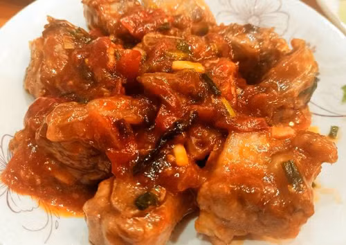 Đun nóng chảo dầu vừa đủ ngập sườn, chiên lửa nhỏ đến khi sườn có màu vàng nâu. Phi thơm hành tỏi, xào cà chua mềm nhuyễn thì cho sườn, gia vị vào. Rim sườn đến khi nước xốt sệt thì tắt bếp, rắc chút hành lá, tiêu là có thể thưởng thức.