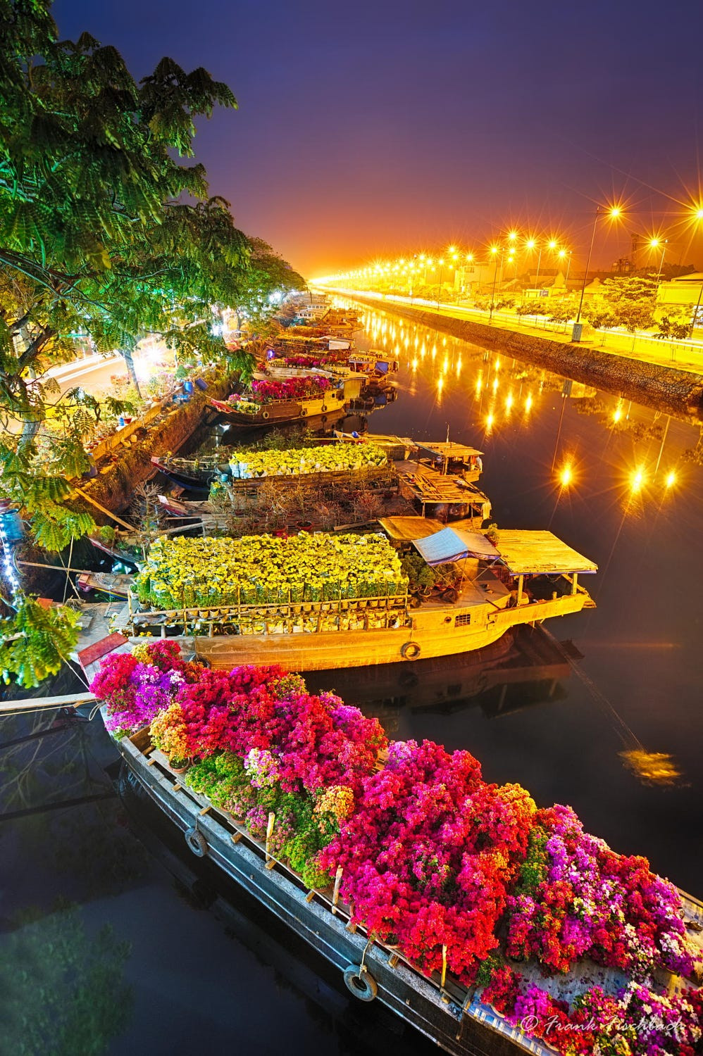 Những con thuyền chở hoa Tết neo đậu trên rạch Bến Nghé, TP HCM. Ảnh: Frank Fischbach - 500px.com