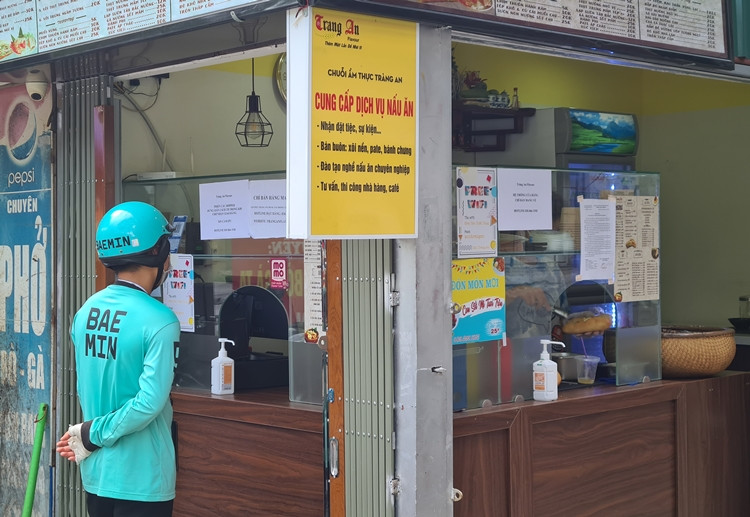 Một shipper chờ đơn hàng để chuyển cho khách. (Ảnh ghi nhận trên phố Tôn Tất Tùng).