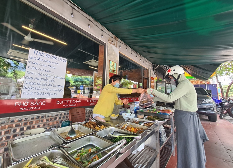 Cả chủ cửa hàng với khách mua đều đeo khẩu trang, kính mắt khi tiếp xúc với nhau. (Ảnh ghi nhận trên phố Huỳnh Thúc Kháng).