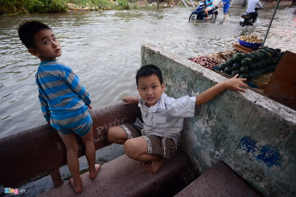 Hai bé Nguyễn Văn Tuấn, Nguyễn Đăng Thịnh ra băng đá ngồi chơi ngắm dòng nước ngập.