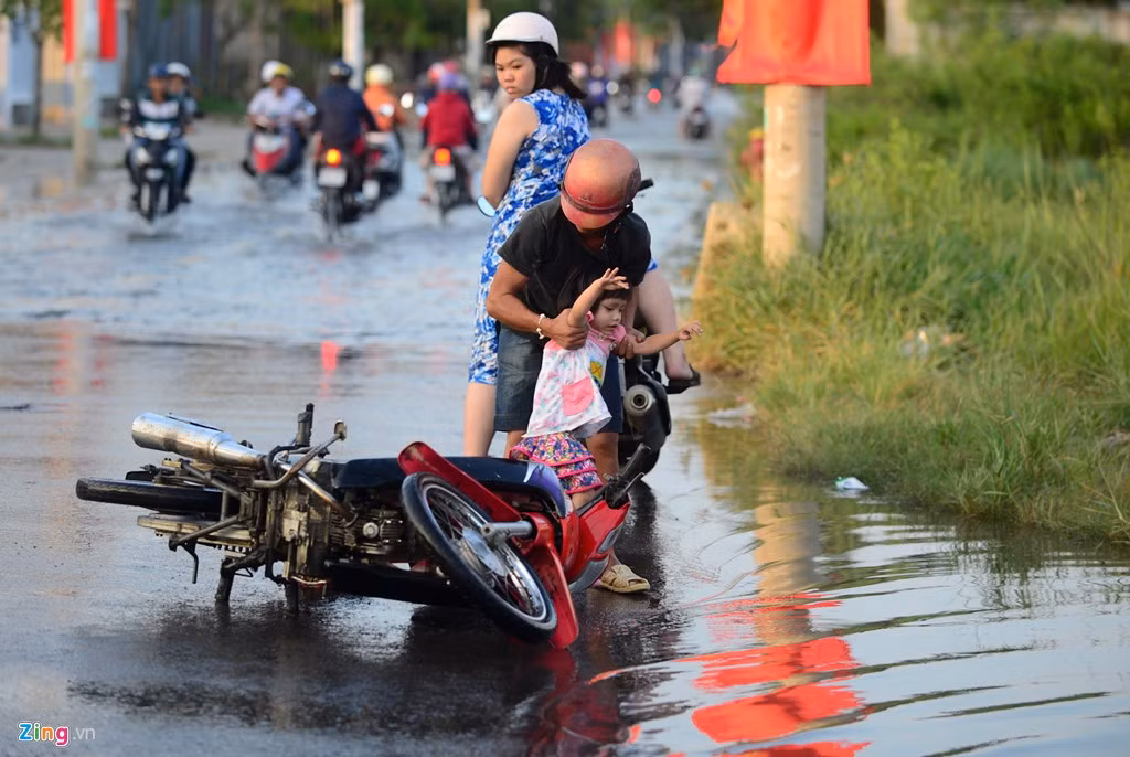 Một người đàn ông đang loay hoay sửa cho nổ máy thì chiếc xe bị đổ suýt trúng vào người em bé.