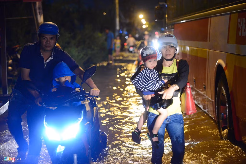 Còn Chị Phan Thị Thu Phương thì lội nước bồng con đi khám bệnh. Gần đó, anh Cao Minh Thiện cũng lội nước dắt bộ về nhà cùng đứa con nhỏ ngồi trên xe.