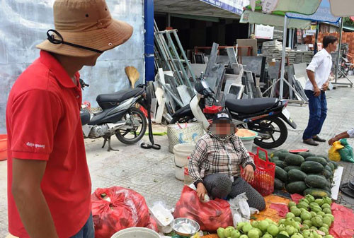 Bà H. và người thanh niên (áo đỏ) bán hàng rong ven đường Nguyễn Hữu Thọ, quận 7 khẳng định mình cũng từng bị đối tượng xưng công an, trật tự đô thị đến thu tiền để được buôn bán.