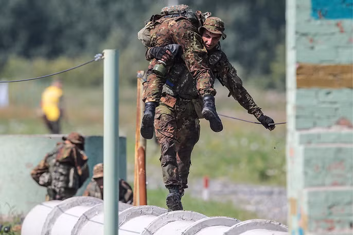Tình huống giả định đồng đội bị thương, các đồng đội khác trong đội thi đấu phải vác theo người bị thương hoàn thành bài thi. Nguồn ảnh: Tass.