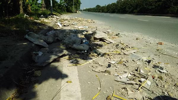 Thậm chí phế thải, bao tải vật liệu xây dựng đổ trộm ra cả lòng đường đại lộ Thăng Long, tiềm ẩn nguy cơ gây tai nạn cho người đi đường.