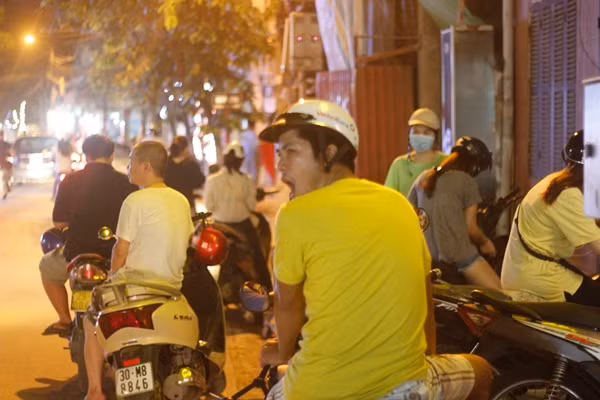 Nhiều người đứng chờ người thân xếp hàng mua bánh tỏ ra mệt mỏi "ngáp ruồi".