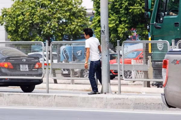 Người đi bộ bất chấp nguy hiểm, cố gắng luồn lách qua hàng rào lưới sắt ngăn cách trên tuyến đường để bắt bằng được xe.