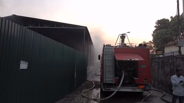 Lực lượng chức năng khẩn trương cho xe chữa cháy tiếp cận hiện trường vụ cháy kho hàng.