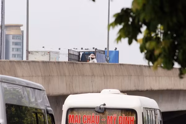 Hình ảnh ghi lại người phụ nữ trên tay cầm điện thoại vừa xem, vừa đứng giữa đường cao tốc trên cao bắt xe khách thay vì vào trong khu vực bến xe Mỹ Đình (cách đó khoảng 200m).