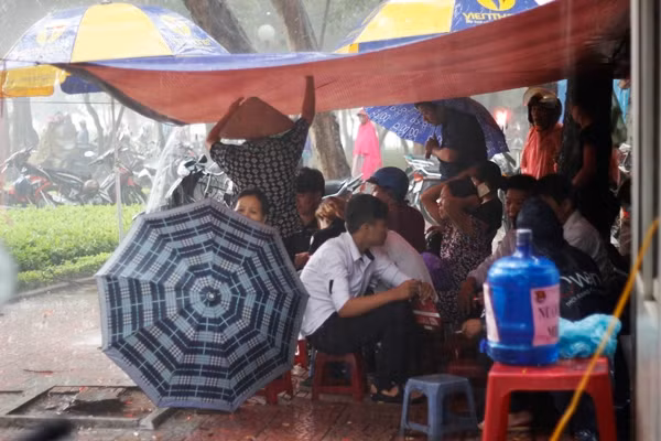 Phụ huynh chen chúc nhau tránh mưa trong một quán trà đá ngay cạnh trường thi.