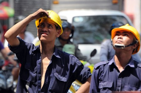 Anh Thế Huy, công nhân cây xanh phải dùng tay che bớt nắng nóng để đốn hạ cây trên đường 3 Tháng 2, quận 10.