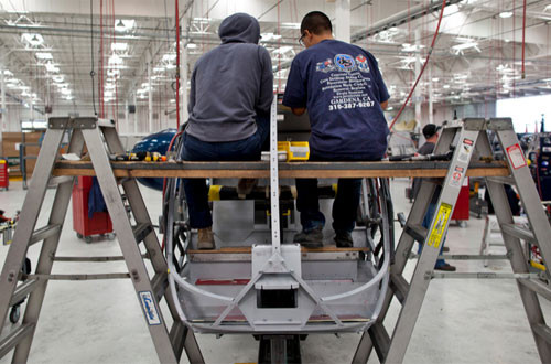 Các nhân viên đang làm việc trên khung của một chiếc trực thăng bên trong nhà máy của hãng Robinson.