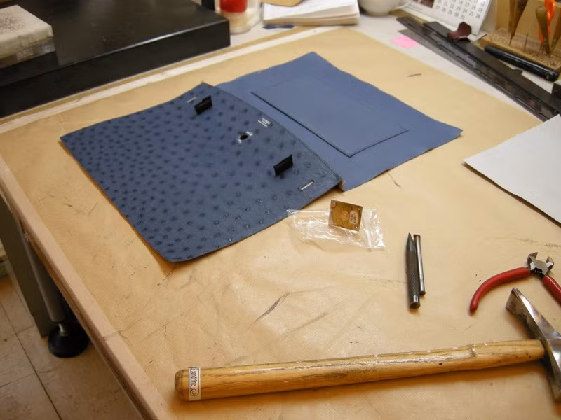 Những chiếc túi Hermes được làm một cách chính xác nhất, không có sự sai lệch dù là ở tỷ lệ rất nhỏ. Những mũi khâu được khâu một cách đặc biệt và hoàn hảo đến nỗi, nếu người thợ trót làm đứt một mối khâu, họ sẽ phải gỡ bỏ toàn bộ những gì đã làm được và khâu lại từ đầu. Trong hình là miếng da đà điểu nhuộm xanh chuẩn bị được khâu thành túi.