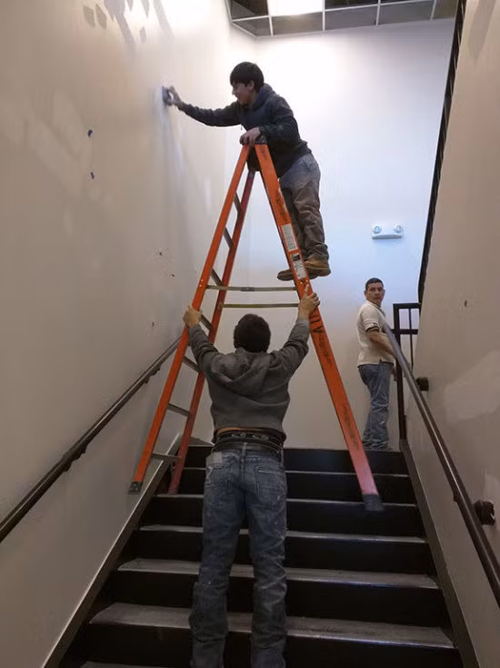 Người đàn ông này làm việc trên một chiếc thang chênh vênh đứng bằng hai chân.