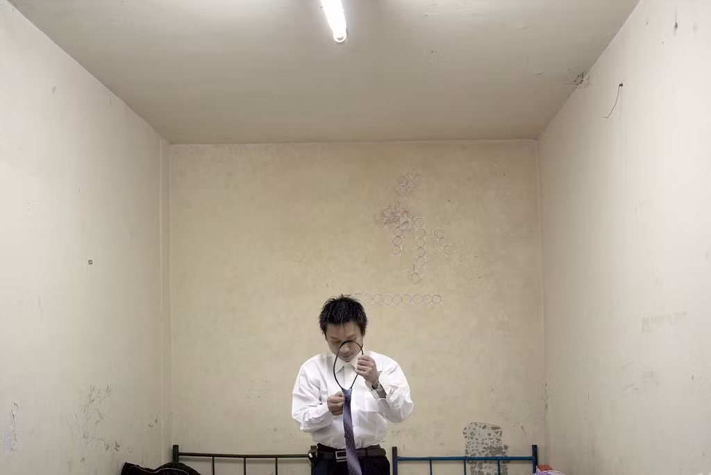 Anh chàng He Bing, 23 tuổi, đang thử một bộ quần áo để chuẩn bị cho buổi phỏng vấn làm nhân viên bán bảo hiểm. Bing mới đến từ thành phố Trùng Khánh và đang sống chung trong một căn hộ tầng hầm nằm ở trung tâm Bắc Kinh với hai người khác.