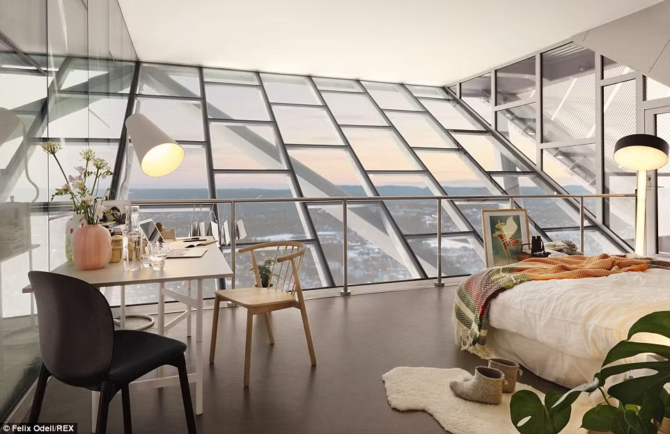 Nội thất căn penthouse trên đỉnh tháp nhảy trượt tuyết gồm một giường đôi, bàn ghế, đèn và một bàn ăn.