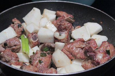 Đun nóng đường và nước lọc, đun sôi đến khi đường chuyển màu vàng cánh gián, đổ hành khô vào phi thơm. Đổ sườn đã luộc sơ vào chảo, dùng đũa đảo đều đến khi đường bám đều ngoài bề mặt sườn. Ảnh: ngoisao.vn.