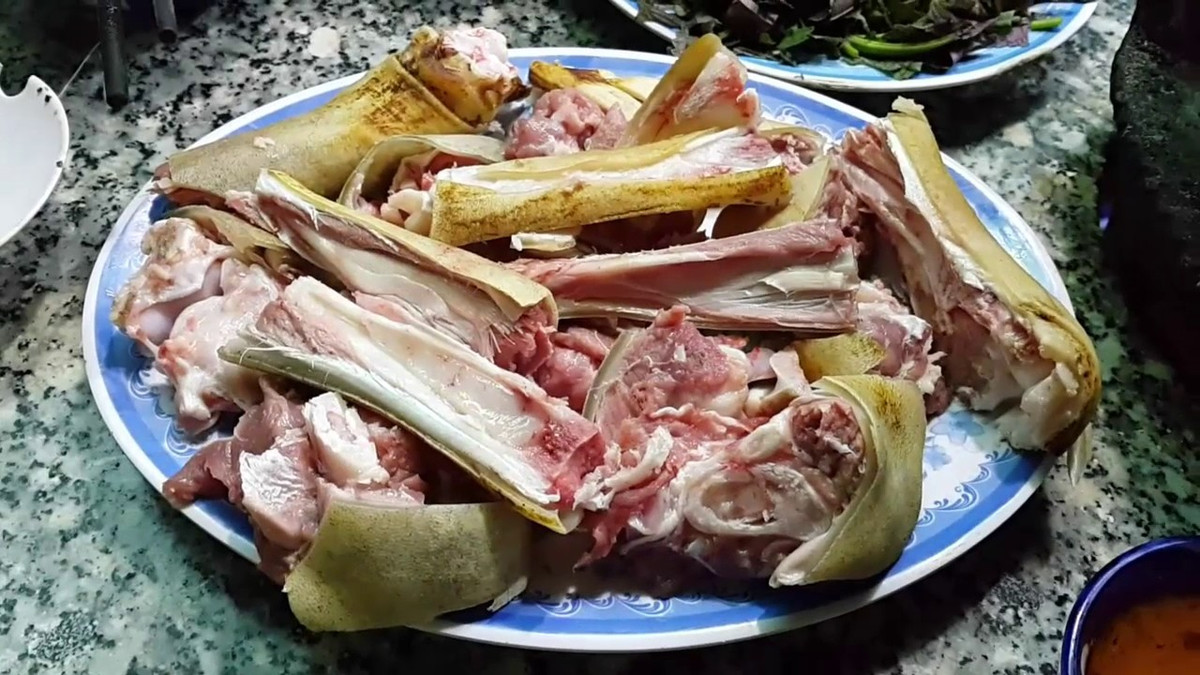 3. Chân dê hầm thuốc bắc. Nguyên liệu: Chân dê, nước xương, thuốc bắc, hành tím, tỏi, gừng, gia vị: ngũ vị hương, bột ngọt, nước tương, đường, muối. Chân dê thui trên lửa. Khi lớp da ngả vàng thì dừng lại, đem đi cạo và rửa sạch rồi dùng dao chặt thành từng miếng vừa ăn. Ảnh: youtube.com.