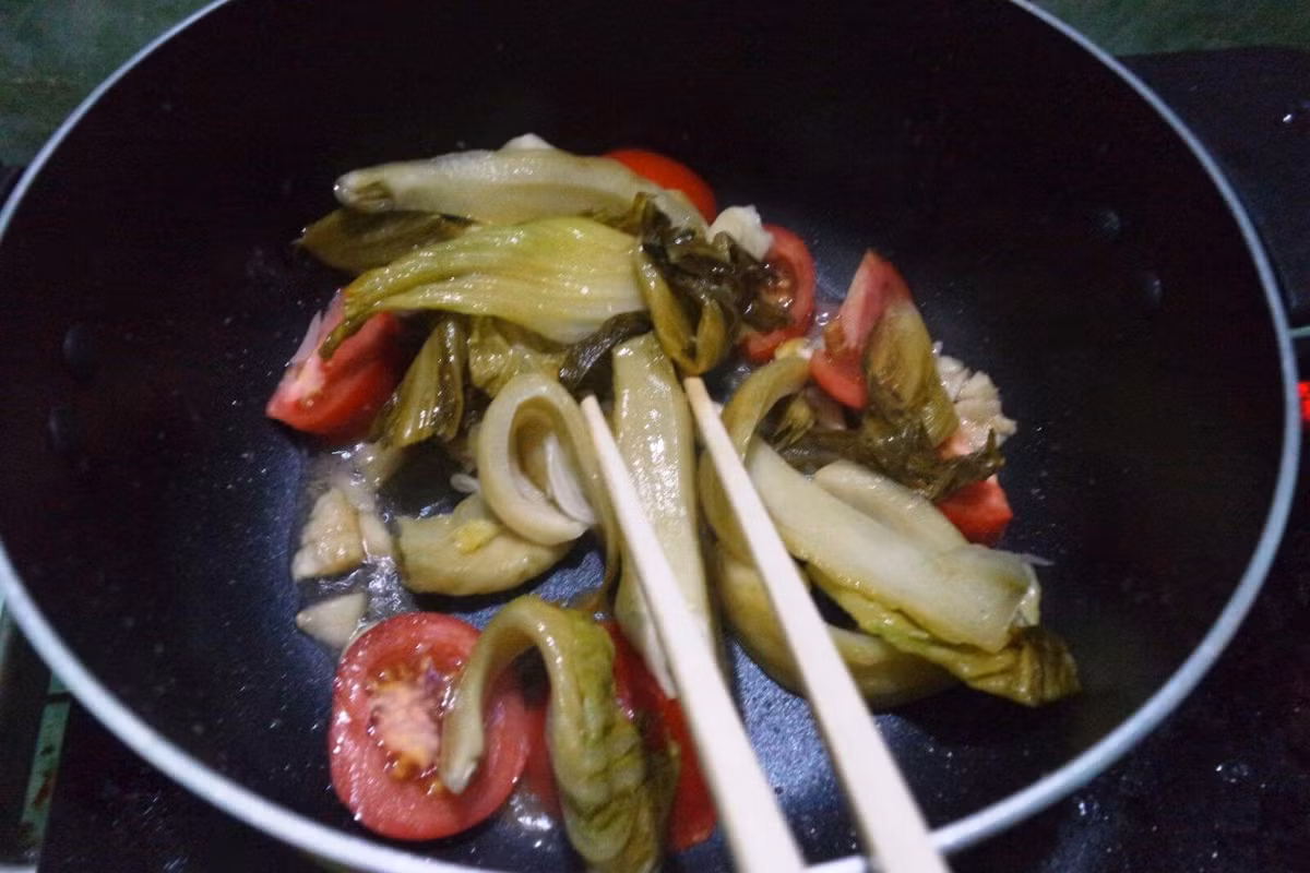 Cho một ít dầu vào nồi, thêm tỏi, ớt, hạt tiêu khuấy đều, cho dưa vào tiếp tục xào. Sau đó cho thêm lượng nước nóng thích hợp và đun trong khoảng 5 phút là sôi. Vớt dưa ra, cho vào bát tô. Ảnh: monngon.tv.