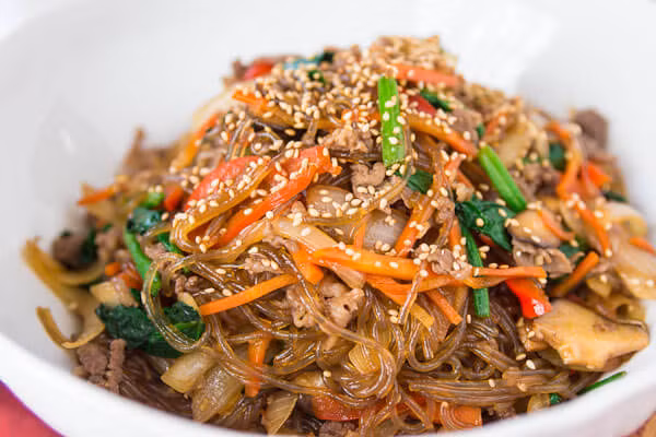 Tiếp theo, cho miến, nước tương, muối, hạt nêm, đường trắng vào, trộn đều, tắt bếp ngay. Rắc mè trắng rang lên trên. Cho món ăn ra đĩa và dùng nóng. Ảnh: Emvaobep.com.