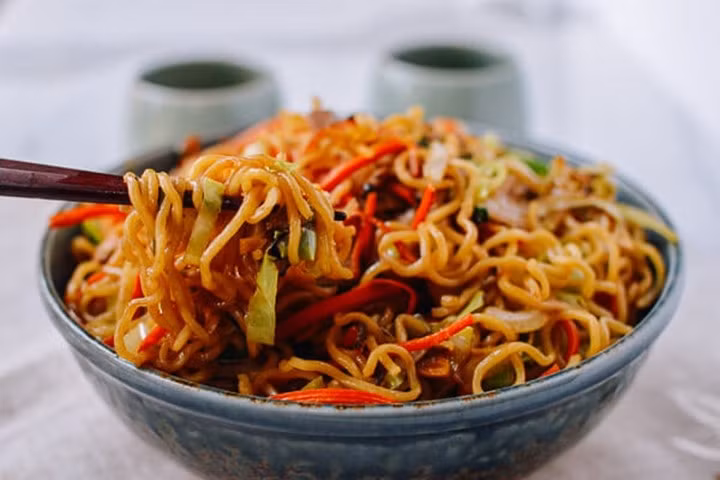 Sau đó thêm mì vào, đảo nhanh tay. Đổ hỗn hợp xì dầu vào xào trong 20 giây. Thêm giá đỗ, đậu Hà Lan tươi, hành lá vào. Đảo thêm 1 phút rồi cho ra đĩa thưởng thức. Ảnh: Toplist.vn.