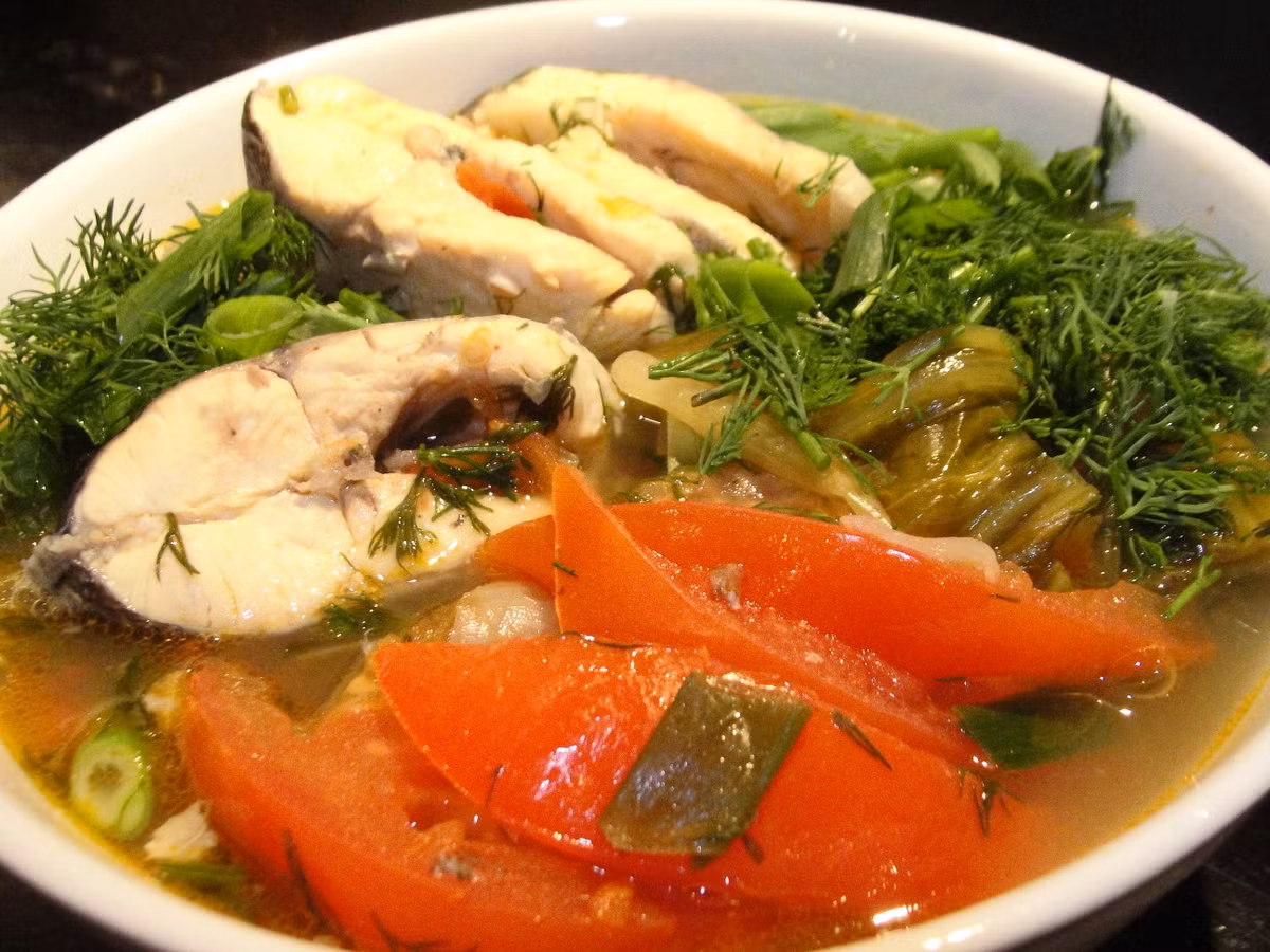 Nước sôi già thì có thể cho cá vào. Đun sôi trở lại và ninh nhỏ lửa 10 phút. Sau đó, bỏ sấu vào nấu thêm 10 phút. Sử dụng muôi thủng để vớt sấu lên rồi dùng thìa dằm nát. Cho lại sấu đã dằm vào nồi. Nêm gia vị vừa ăn. Đun sôi thêm 2-3 phút nữa. Cho hành, thì là vào là hoàn thành. Ảnh: Tinmoi.vn.