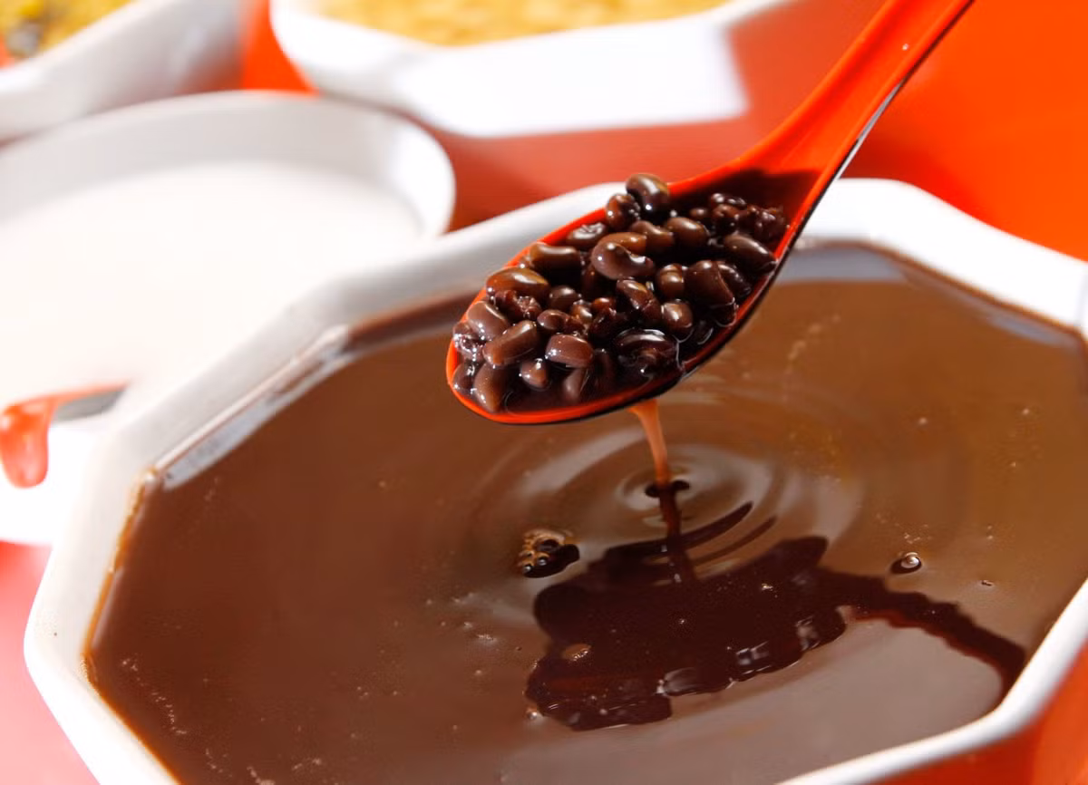 Chắt bớt nước trong nồi chè ra bát, rồi đổ đường vào khoảng 200-300gr, đun cho tan đường, đảo nhẹ nhàng rồi tiếp tục đậy vung, đun trong vòng 10 phút cho đường ngấm vào đỗ. Chế thêm nước vào nồi chè, rồi đun sôi trở lại. Đổ nước cốt dừa vào nồi chè, đun sôi tiếp rồi tắt bếp. Ảnh: JAMJA.vn.