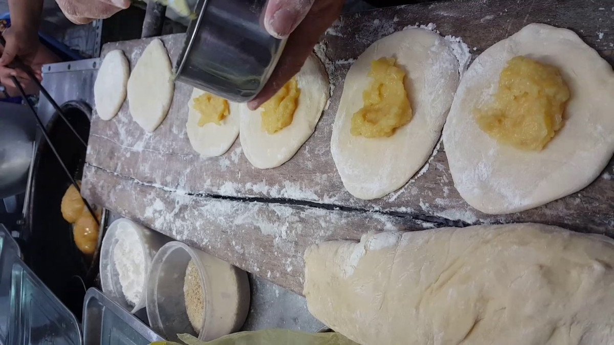 Dùng lòng bàn tay nhồi đều gom bột về trung tâm cục bột. Sau 20 phút bột đã mịn mặt gom bột thành trái banh, cho trở lại vào thố, bọc màng plastic để chỗ ấm áp khoảng 1 giờ hoặc tới khi bột nở gấp đôi ban đầu.Lấy bột ra nhào sơ. Chia thành phần nhỏ. Nhồi sơ lại từng phần túm lại thành trái banh 50g. Lăn bánh vào mè trắng. Ảnh: youtube.com.