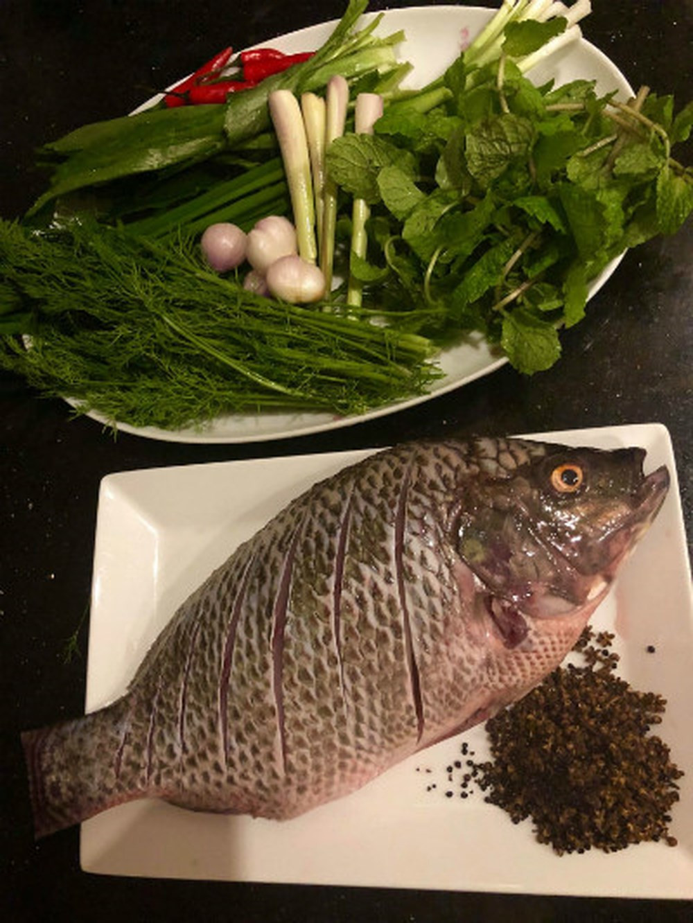 1. Cá nướng mắc khén. Nguyên liệu: Cá rô phi, mắc khén rang chín, giã nhỏ, hạt dổi, hành khô, sả, thì là, húng quế, ngổ, mùi tàu, ớt tươi, riềng, hành lá. Cá rửa sạch, khía hai bên mặt ngoài. Nên mổ cá từ lưng để khi nhồi rau nướng sẽ không bị rớt ra ngoài. Các loại rau rửa sạch để ráo nước.