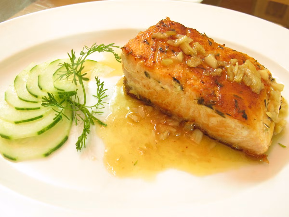 Cho nước cốt chanh vào đun lớn lửa với nước sốt bơ còn trong chảo. Rưới nước sốt lên cá. Có thể thêm tỏi băm lúc chiên cá cho thơm. Ảnh: BepGiaDinh.com.