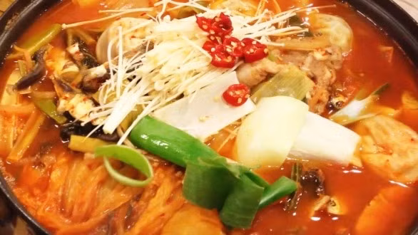 Hành tây bổ làm 4, cắt miếng ngang. Cho hành tây vào nồi nước dùng, mở vung đun đến khi hành tây chín thì vớt bỏ. Cho thịt gà đã ướp vào nồi nước dùng. Khi nước dùng sôi, thêm nước măng và măng ớt vào. Ảnh: 102food.vn.