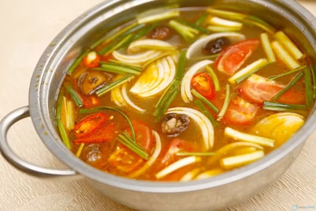 Phần cà chua còn lại xếp cùng rau lát nữa cho sau khi ăn lẩu. Khi cà chua chín mềm, cho măng chua cùng chút bột nêm vào xào kĩ. Tiếp đến cho nước dùng vào đun sôi. Nước sôi, cho thịt me ở trên cùng chút đường phèn, sa tế vào nêm nếm vừa ăn. Ảnh: MomKitty.com.